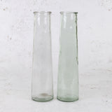 A pair of tall, cylindrical glass vases in clear and very pale green.