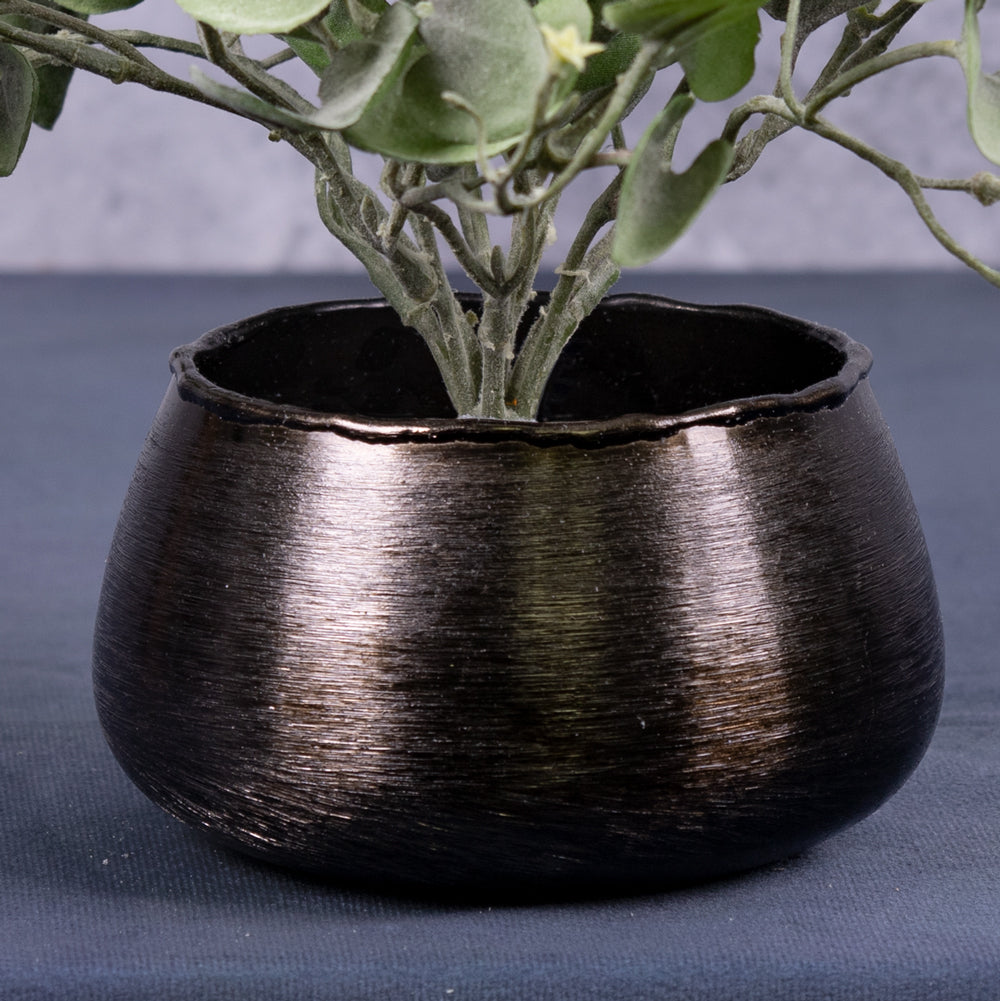 An artificial dichondra falls plants in a black, brushed metal pot cover