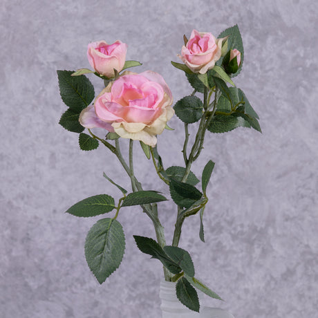 A faux pink rose spray shown in a frosted white glass vase