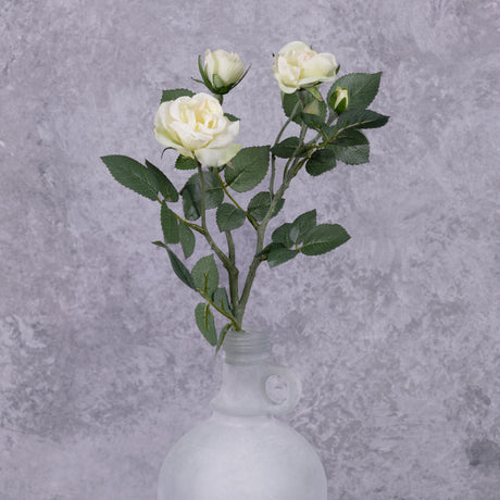 A faux white rose spray shown in a frosted white glass vase