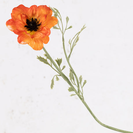 A faux anemone flower and stem with leaf detail, in bright orange.