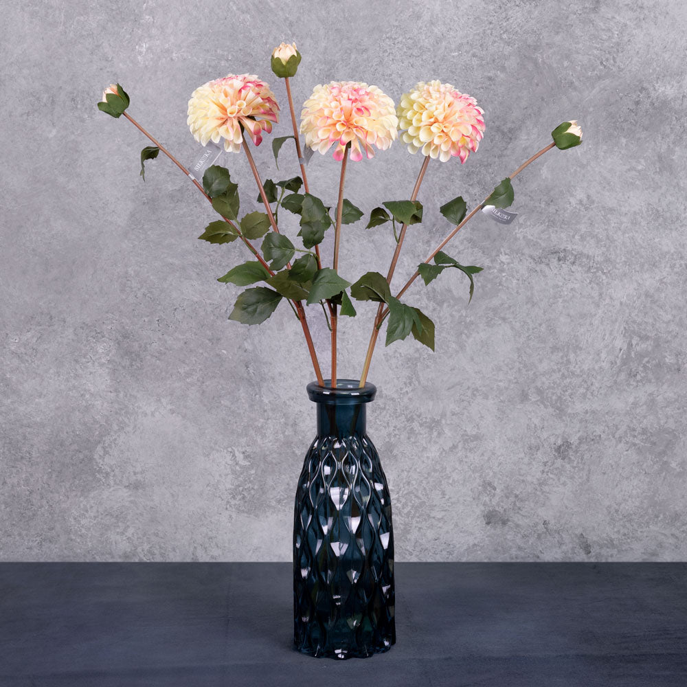 Three faux dahlia sprays in a creamy and pink colour, displayed in a blue glass vase