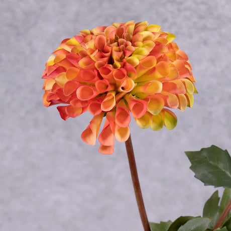 A close up of a faux dahlia flower in a rich orange-red colour