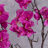 A close up of bright pink flowers on a faux Bougainvillea stem