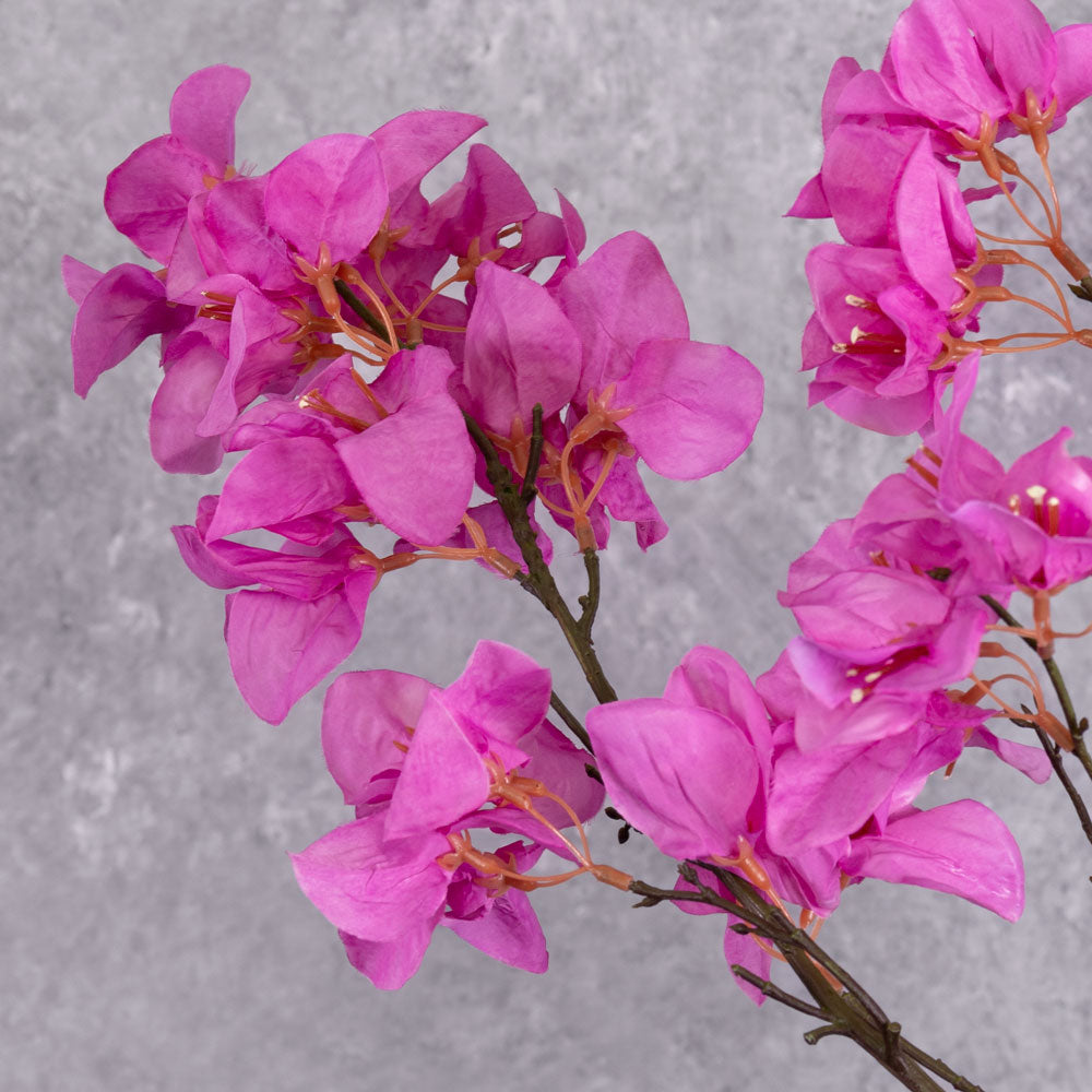 A close up of a faux Bougainvillea spray with bright pink flowers over multiple branchlets