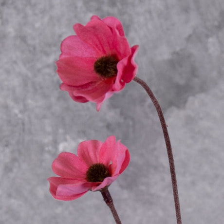 A close up of a faux Cosmos flower spray with pink blooms