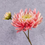 A faux chrysanthemum stem in a warm pink that graduates to a pale pink and then yellow towards the centre, along with an emerging flower to the side