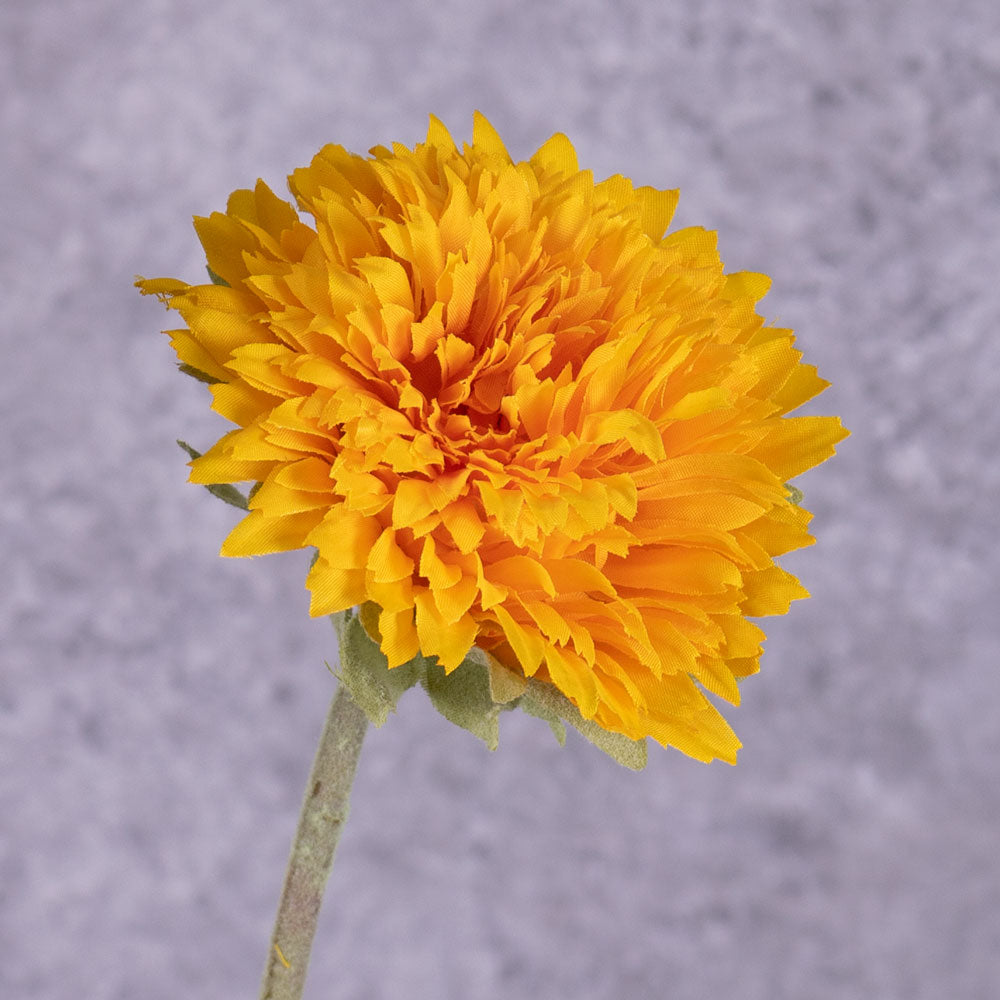 A close up of a single faux sunflower in rich yellow