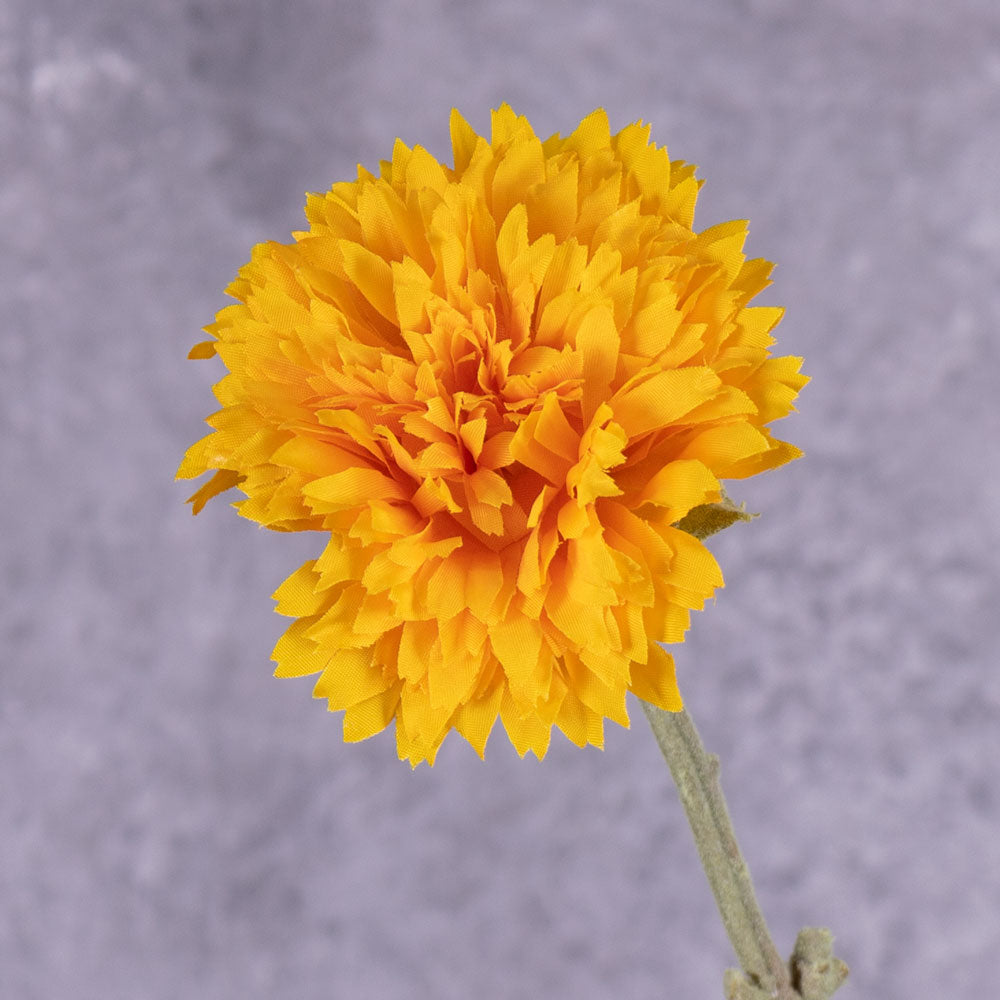 A close up of a single faux sunflower in rich yellow