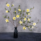 3 individual A faux yellow rose spray branches displayed in a blue, glass vase.