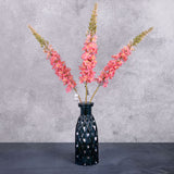 Three faux, fox tail lilies in a warm pink colour, shown in a blue glass vase