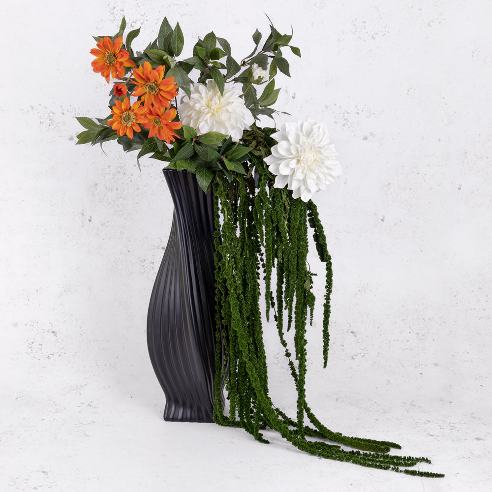 Amaranthus in dark green, displayed in a black vase with orange and white faux flowers and green foliage.