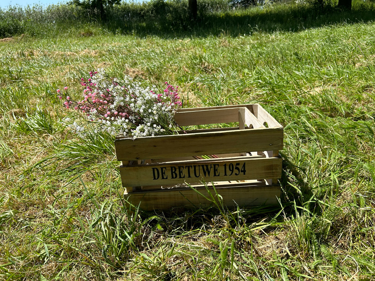 Pink and white faux gypsophila bunches shown in a wooden crate within a sunny meadow