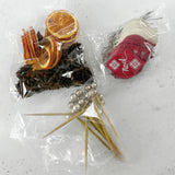 Bags containing dried orange slices, star anise, picks and wooden shapes