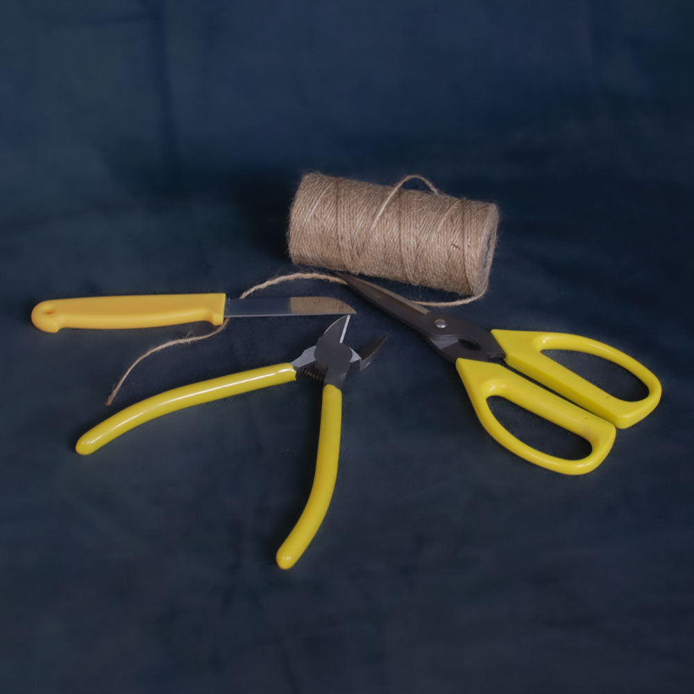 A florist's knife, scissors, wire snips, and a reel of natural jute twine.