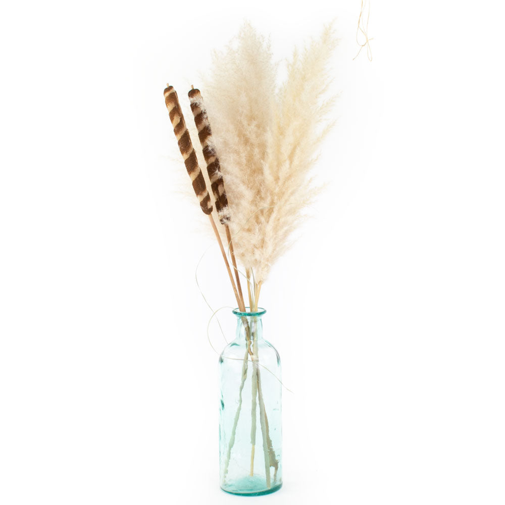 a blue-green glass bottle with an intentionally imperfect finish, showing air bubbles within the glass, and a slightly distorted finish, displaying dried bullrushes and fluffy pampas grass.