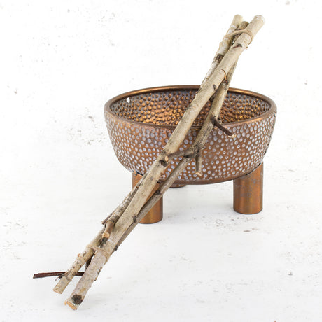 A bunch of 3 by 60cm long birth twigs leaning against a copper bowl.
