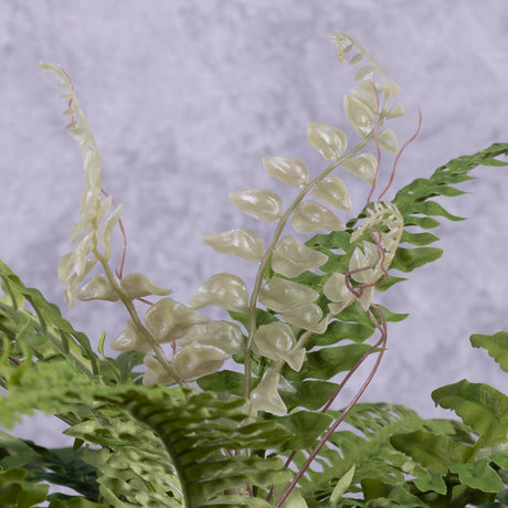 A close up of the leaves of an artificial Boston or sword fern in a terracotta pot.