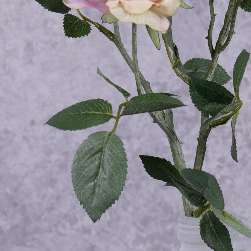 A close up of the leaf detail on a faux pink rose spray