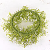 An artificial gypsophila wreath with white flowers, on a green plastic frame.