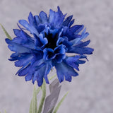 A close up of a faux cornflower in a deep blue colour