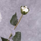 A close up of a faux, white dahlia bud, with leaves