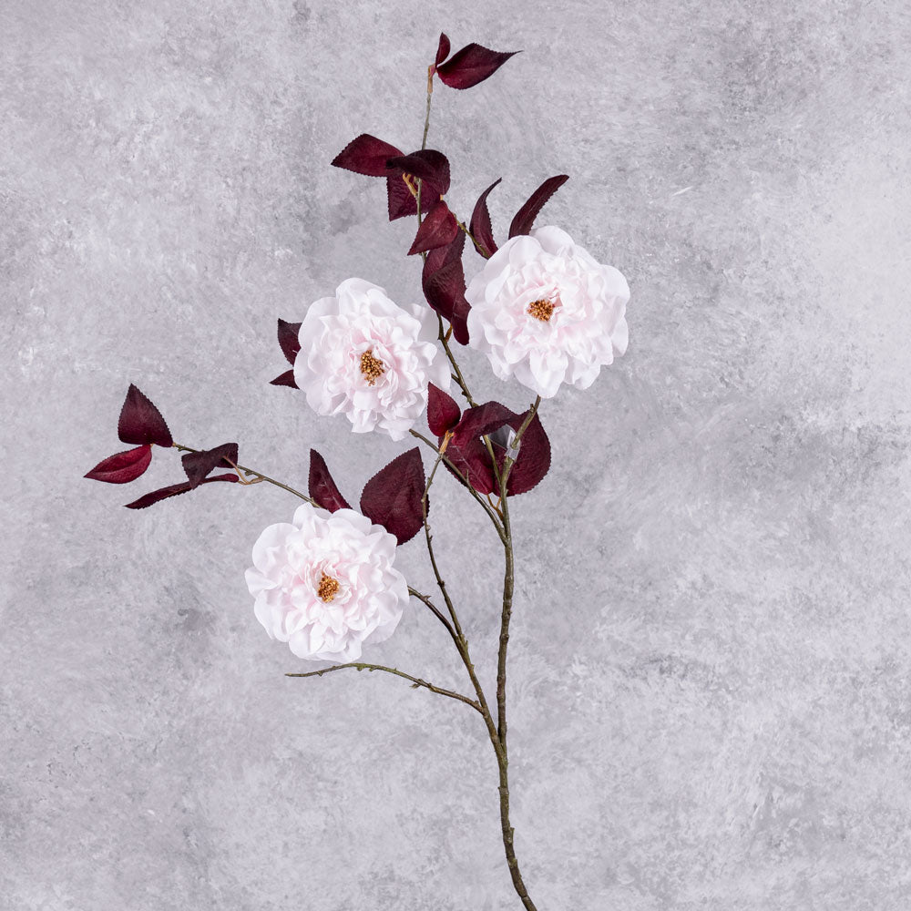 A faux camelia spray, in white with red leaves, displaying three flowers