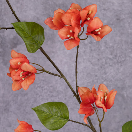 A close up shot of three flower clusters from a faux bougainvillea spray, in an acidic orange-red colour