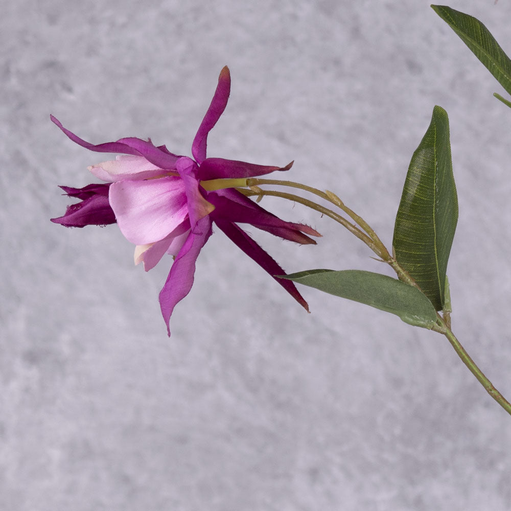 A close up of a faux aquilegia flower in a warm purple hue, and pinkish centre