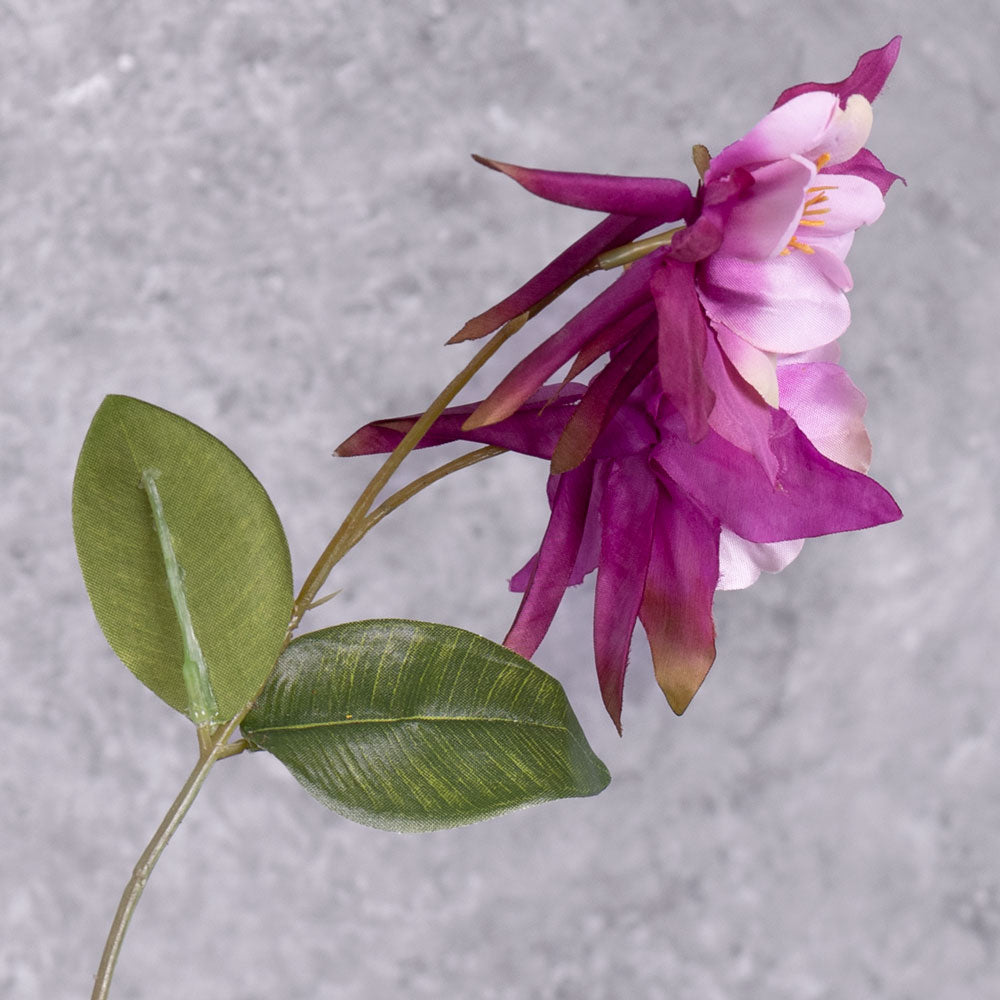 A close up of a pair of faux aquilegia flowers in a warm purple hue, and pinkish centre, and leaves over several branchlets