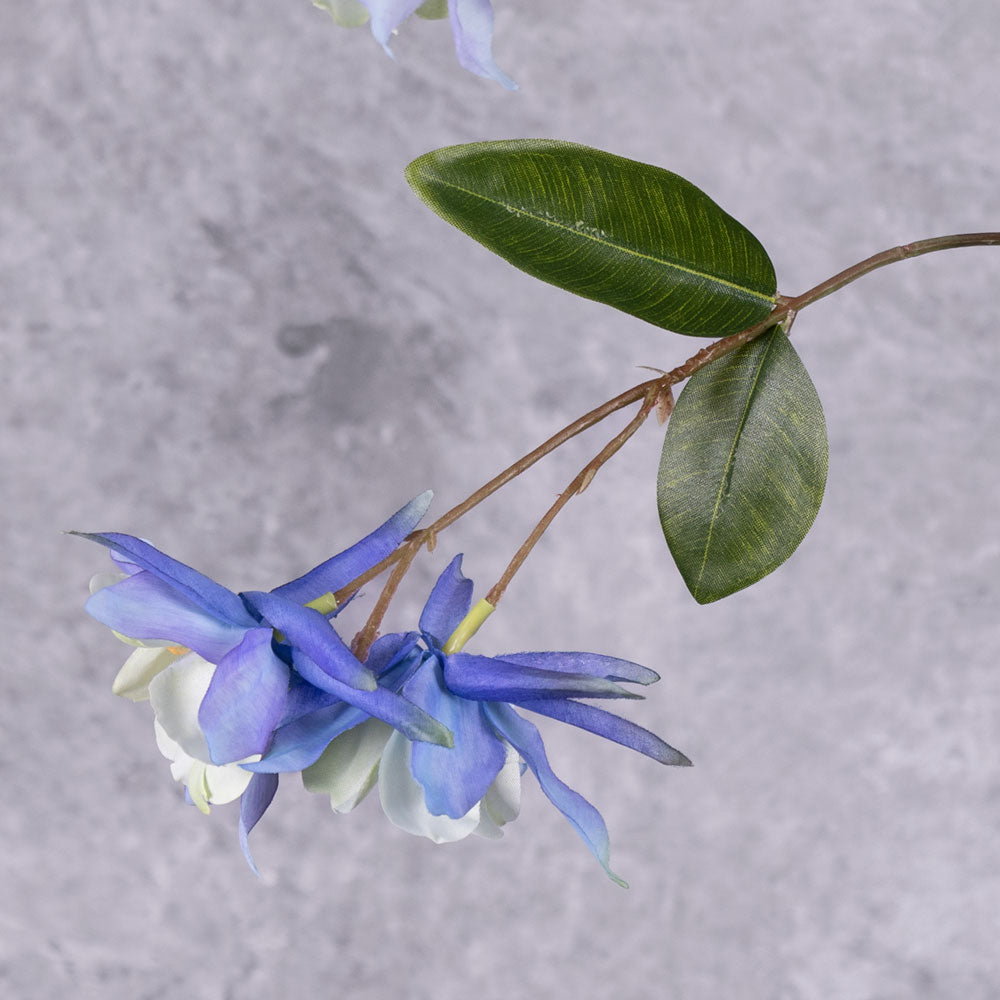 A close up of a pair of faux aquilegia flowers in a blue hue, and white centre