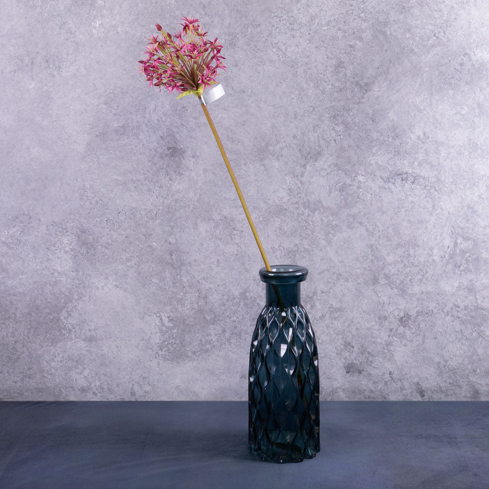 A single faux allium stems with a deep pink coloured flower plume, displayed in a blue glass vase