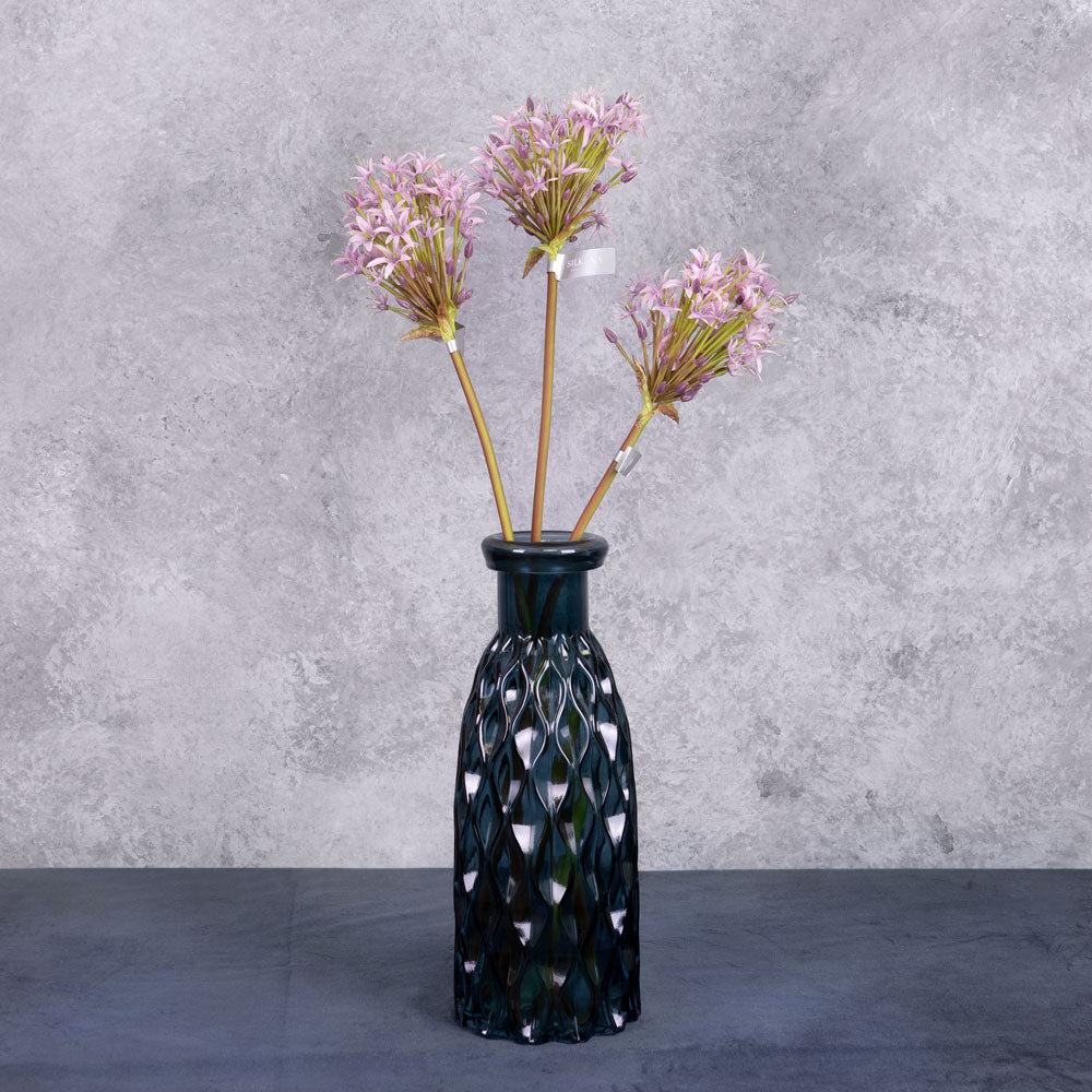 A group of three faux allium stems with lilac coloured flower plumes, displayed in a blue glass vase