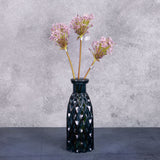 A group of three faux allium stems with lilac coloured flower plumes, displayed in a blue glass vase