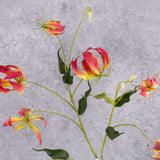 A close up of a faux pink and yellow coloured Gloriosa spray