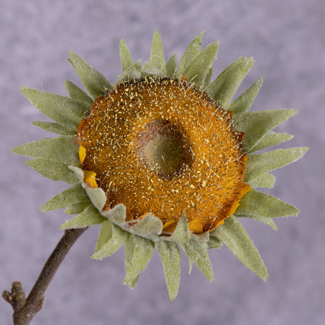 A close up of a single, faux, sunflower head in rich yellow