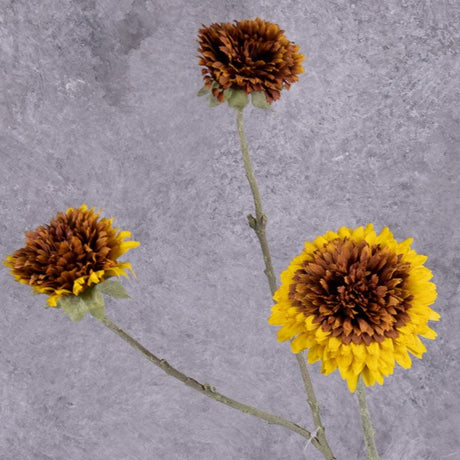 A faux sunflower spray with three separate flowers of different sizes