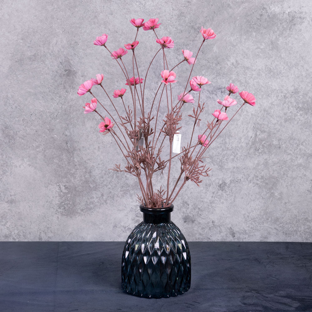 Three faux Cosmos flower spray stems, with pink blooms, shown in a blue glass vase