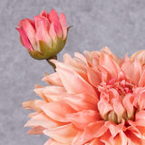 A close up of a single, faux dahlia spray, with a rich, salmon-coloured flower and emerging bud
