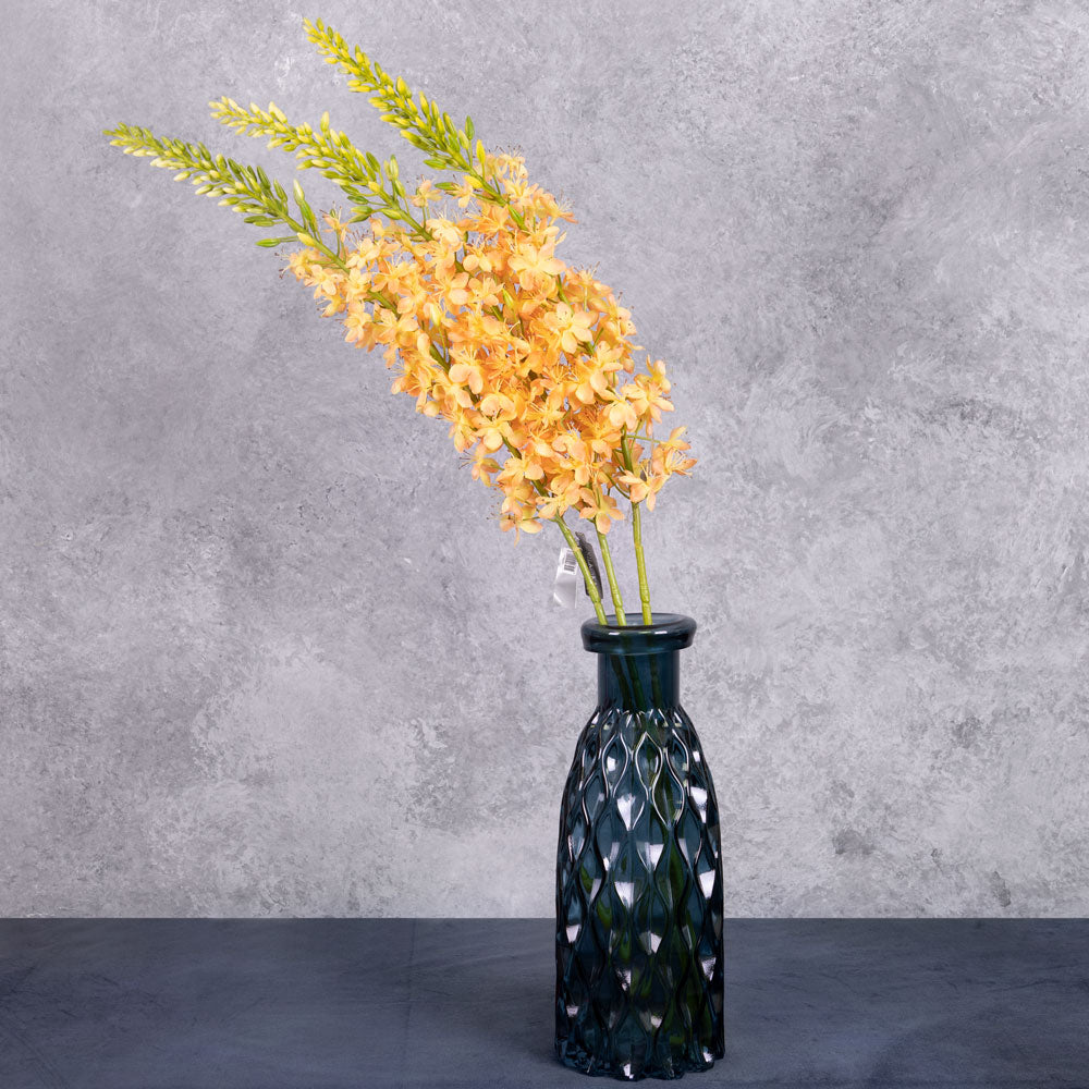 Three faux eremurus stems with peachy-yellow flowers, shown in a blue glass vase