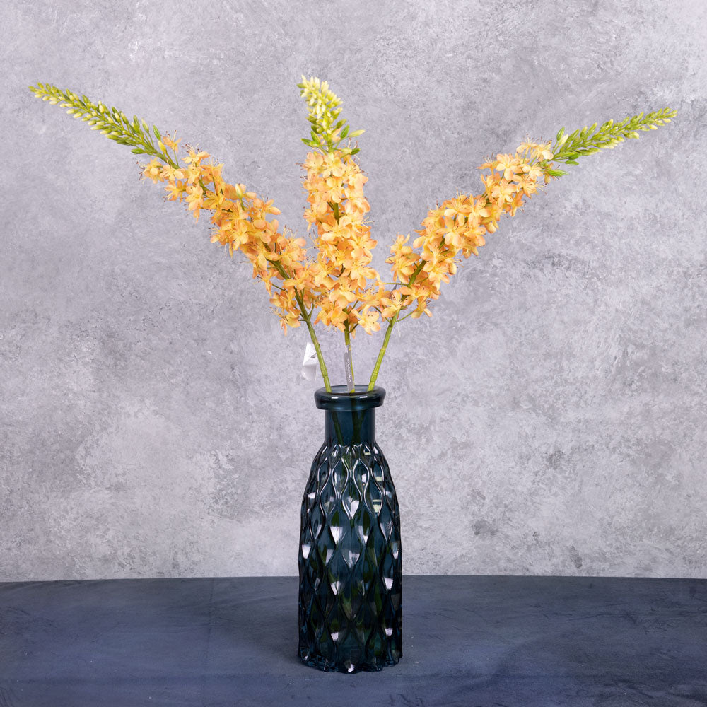 Three faux eremurus stems with peachy-yellow flowers, shown in a blue glass vase