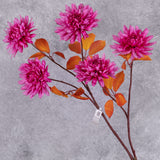 A close up of some bright pink, faux chrysanthemum flowers with orange-red leaves