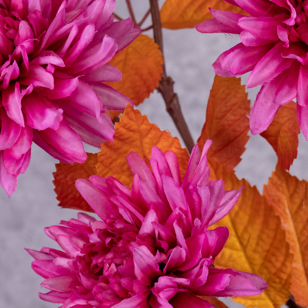 A close up of some bright pink, faux chrysanthemum flowers with orange-red leaves