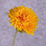 A close up of a single faux sunflower in rich yellow