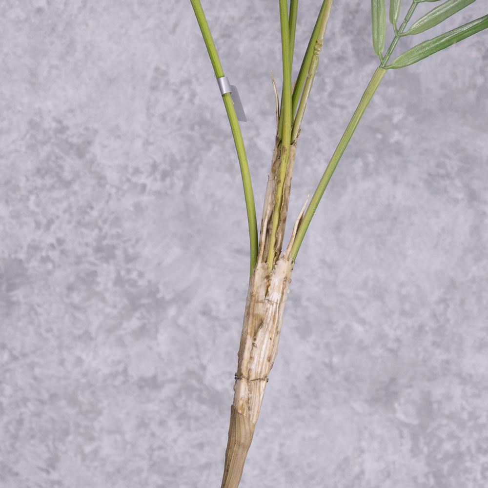 A close up of the main stem of a faux palm bush as it branches into three fronds