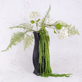 Amaranthus in an acidic green, displayed in a black vase with fern and viburnum flowers.