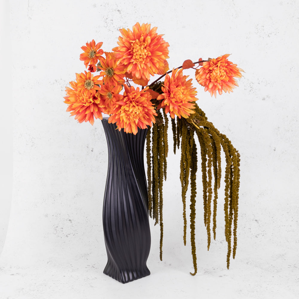 Almond green amaranthus in a black vase with faux orange flowers.