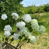 A group of faux viburnum sprays in both green and white, and plain white flower options. The scene is set in a meadow against the backdrop of blues skies and bright sunshine.