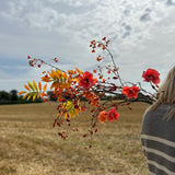 These beautiful artificial florals are in a range of orange and yellow tones, contrasted by a cloudy sky and stubble field.