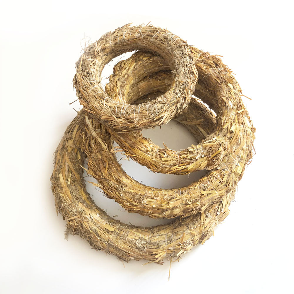 A collection of different sized wreath bases made from natural straw.